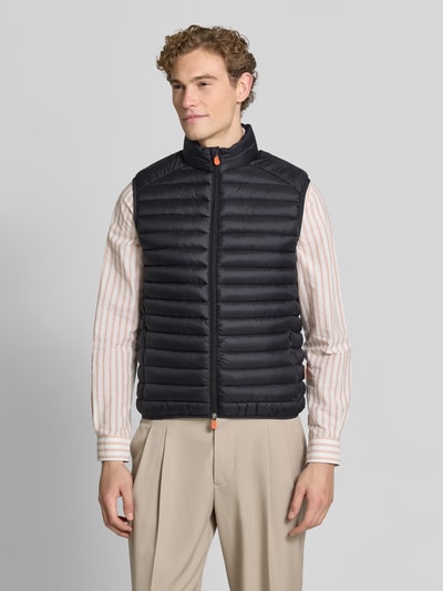Männermodel trägt schwarze Steppweste mit Zweiwege-Reißverschluss Modell 'ADAM' von Save The Duck, Regular Fit, Ganzkörperansicht von vorne.