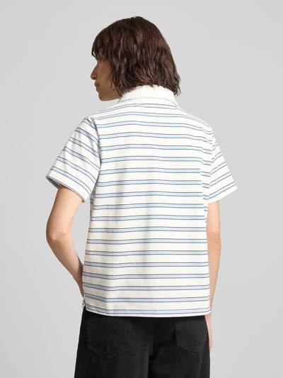 Frauenmodel trägt Poloshirt mit kurzer Knopfleiste Modell 'Asla' von My Essential Wardrobe aus Baumwoll-Mix, schmale Streifen, rückenlange 63 cm, Körpernahe Passform, Ganzkörperansicht Rückansicht.
