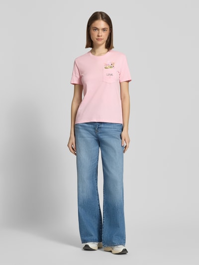Frauenmodel trägt Regular Fit T-Shirt aus reiner Bio-Baumwolle Modell 'POLLY' von Only in Optik: Unifarben mit Statement-Print-Applikation, Motiv-Stitching und Brusttasche, gefertigt aus Jersey, Ganzkörperansicht von vorne.