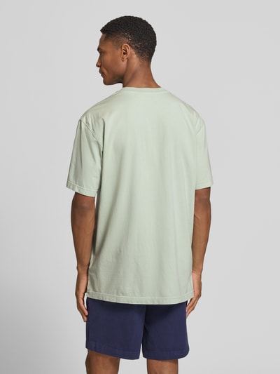 Männermodel trägt Relaxed Fit T-Shirt aus reiner Bio-Baumwolle Modell 'ICONIC MAARKOS GD' von Armedangels in Unifarbe, Ganzkörperansicht Rückansicht.