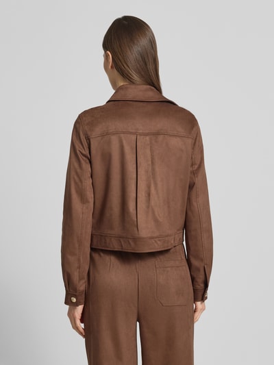 Modelka nosi kurtkę 'Jacke mit Umlegekragen' od Oui, elastyczna mieszanka materiałów, prosty krój, nakładane kieszenie, zapięcie na guzik, długość tyłu w rozmiarze 36: 49 cm, szerokość ramion w rozmiarze 36: 39 cm, szerokość klatki piersiowej w rozmiarze 36: 43 cm, długość rękawów w rozmiarze 36: 61 cm, kolor brązowy, widok całej sylwetki z tyłu.