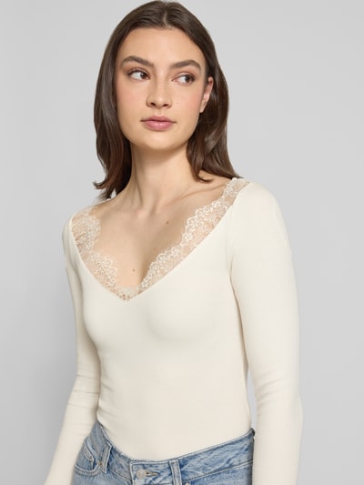 Frauenmodel trägt Longsleeve mit V-Ausschnitt und Spitze von Gina Tricot, cremefarben, Slim Fit, Feinripp, Baumwoll-Mix, Nahaufnahme Oberkörper.