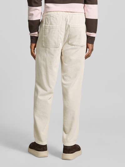 Männermodel trägt Straight Fit Cordhose aus reiner Baumwolle Modell 'Padow' von American Vintage, helle Farbe, samtartige Textur, Gesäßtaschen, elastischer Bund, Ganzkörperansicht Rückansicht.