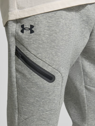 Männermodel trägt Regular Fit Sweatpants mit Logo-Print Modell 'Unstoppable' von Under Armour in Grau, elastischer Material-Mix, Nahaufnahme Oberkörper.