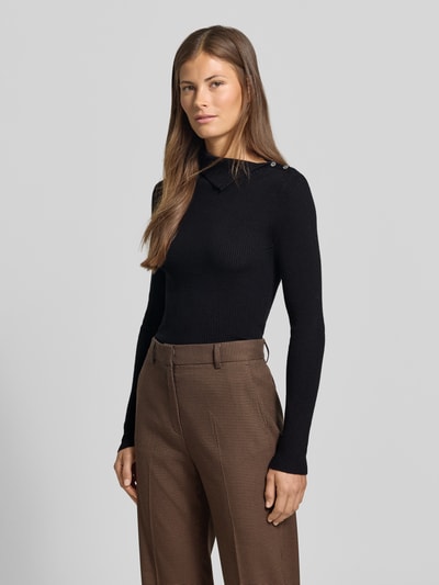 Frauenmodel trägt schwarzen Slim Fit Pullover aus Viskose-Mix in Strick-Optik von MYON, braune Hose, Nahaufnahme Oberkörper. Rückenlänge bei Größe 36: 62 cm, Ärmellänge: 68 cm, Knopfleiste.