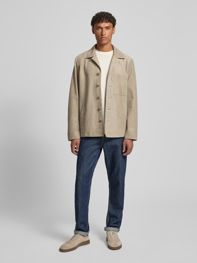 Männermodel trägt Regular Fit Ziegenlederjacke mit Brusttasche van Marc O'Polo in wildleerlook met platte kraag, knoopsluiting, labelapplicatie, borstzak en zij-steekzakken, suède textuur, lichtbeige kleur, materiaalverwerking geitenleer, lange mouw, ganzkörperansicht van voren