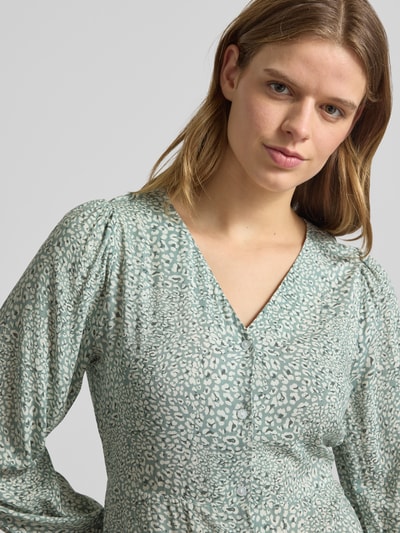 Frauenmodel trägt tailliertes Damen Freizeitkleid aus reiner Viskose Modell 'EVIDA' von Only, Optik: Allover-Muster, V-Ausschnitt, Langarm mit Ballonärmel und Knopfleiste, zart grün-gemustertes Material, Nahaufnahme Oberkörper.