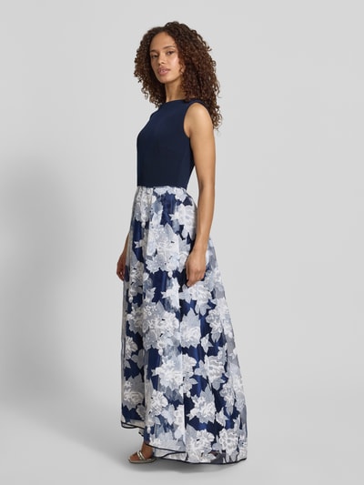 Frauenmodel trägt Abendkleid mit rückseitigem V-Ausschnitt von Christian Berg Cocktail in Dunkelblau und Weiß, Material-Mix mit Stretch-Anteil, Taillierter Schnitt, Maxikleid mit U-Boot-Ausschnitt, florales Muster, rückseitiger Reißverschluss, Rückenlänge bei Größe 36: 130 cm, Brustweite 47 cm, Ganzkörperansicht von vorne.