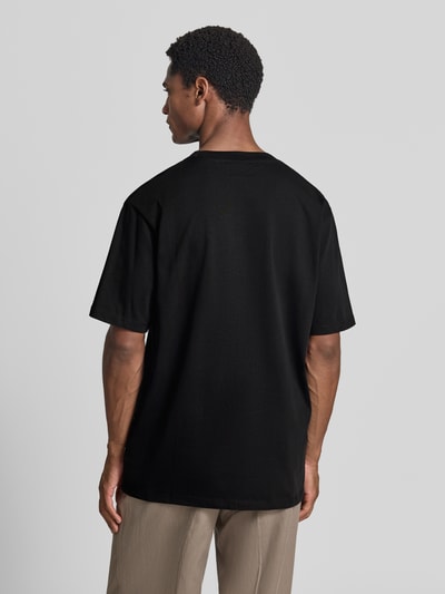 Männermodel trägt Oversized T-Shirt aus reiner Baumwolle von Lindbergh in Schwarz, leicht überschnittene Schultern, Rückenansicht, Kontext: Herren T-Shirt von Lindbergh, reine Baumwolle, Oversized, leicht überschnittene Schultern, Halbärmeliges-Design, Rückenlänge bei Größe M 70 cm