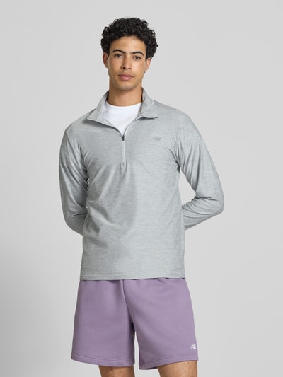 Männermodel trägt Regular Fit Sweatshirt mit Troyer-Kragen von New Balance, leichter Elastischer-Material-Mix, Logo-Print, Ganzkörperansicht von vorne. Rückenlänge bei Größe M: 69 cm.