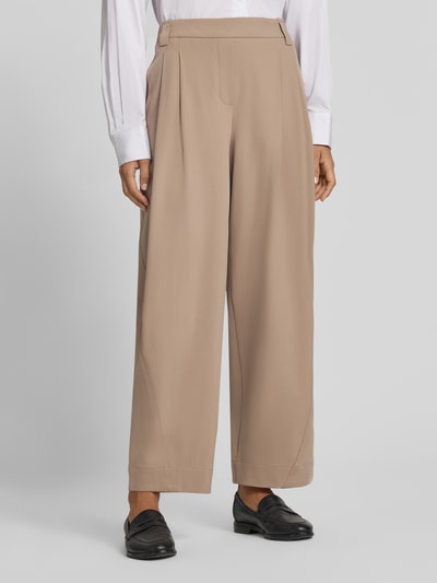Frauenmodel trägt relaxed Fit Gerade Hose mit Bundfalten Modell 'Metta' von OPUS PANTS in Beige, glatte Textur, Nahaufnahme Unterkörper.