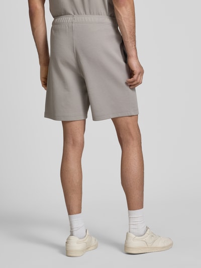 Männermodel trägt Shorts mit elastischem Bund und Label-Stitching von CHAMPION im Regular Fit aus Baumwoll-Mix, Ganzkörperansicht Rückansicht.