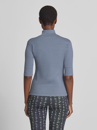 Frauenmodel trägt Slim Fit T-Shirt aus Baumwoll-Mix mit Stehkragen von Marc Cain in Blau, 1/2-Arm, elastisch, Rückenlänge 54 cm, Ganzkörperansicht Rückansicht.
