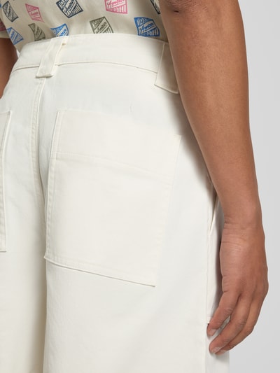Mężczyzna nosi Loose Fit Bermudas aus Bio-Baumwoll-Mix Modell 'HOTEL AMOUR' od SELECTED HOMME, jednokolorowy, denim, detal label patch, 5 kieszeni, kremowy, z bliska fragment tylnej części.