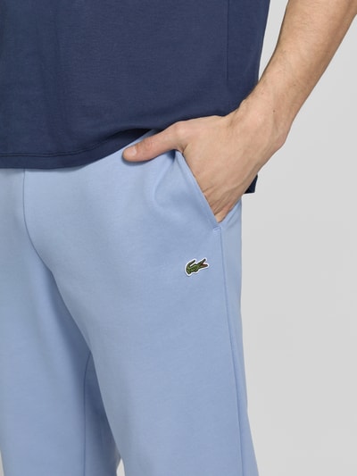 Mężczyznamodel nosi Regular Fit Sweatpants aus Baumwoll-Mix od Lacoste, jasnoniebieski kolor, logo, bawełniany materiał, krój regular fit, zbliżenie na kieszeń