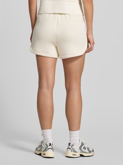 Frauenmodel trägt Sweatshorts aus Viskose-Mix von VARLEY in Creme, lockere Passform, elastischer Bund, Ganzkörperansicht Rückansicht.