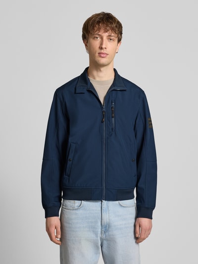 Männermodel trägt Regular Fit Bomberjacke mit Stehkragen Modell 'Parker' von Jack & Jones, Dunkelblau, Softshell, Ganzkörperansicht von vorne.