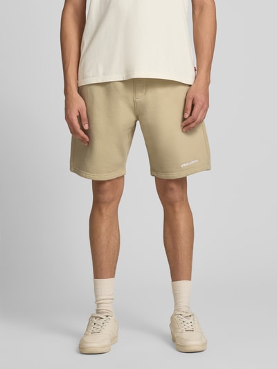 Männermodel trägt Shorts mit elastischem Bund und Logo-Stitching von Pegador aus Baumwoll-Mix, Loose-Fit, Eingrifftaschen, Ganzkörperansicht von vorne.