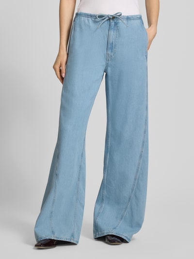 Frauenmodel trägt Low Rise Jogpants mit weitem Bein von Guess Jeans aus Baumwoll-Lyocell-Mix, hellblau, Tunnelzug, Ganzkörperansicht von vorne.