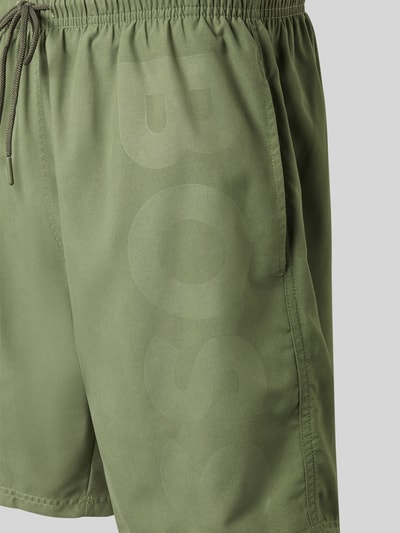 Produktfoto, Badeshorts mit Label-Schriftzug Modell 'ORCA' von BOSS in Optik: Unifarben, elastischer Bundabschluss, seitliche Eingrifftaschen, Gesäßtasche, Verschluss: Tunnelzug, glatte Textur, grünes Design.