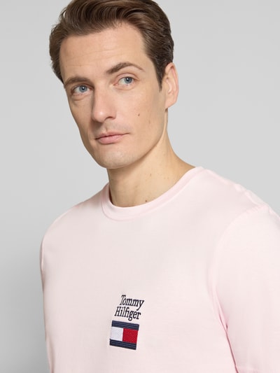Männermodel trägt Regular Fit T-shirt aus reine katoen Model 'BRAND LOVE TEXT' von Tommy Hilfiger, look: effen, korte mouw, ronde hals, labelstitching, gestikt logo, puur katoen. Nahaufnahme Oberkörper.