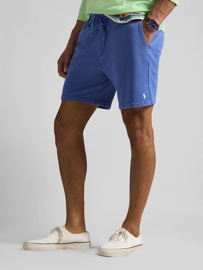 Männermodel trägt Regular Fit Sweatshorts aus Baumwoll-Mix von Polo Ralph Lauren in Blau mit Logo-Stitching, seitlichen Taschen, Ganzkörperansicht von vorne.