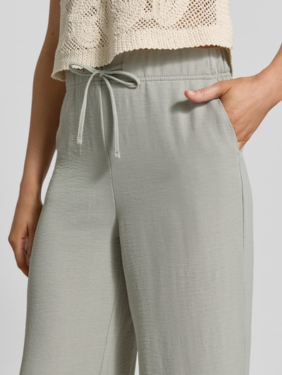 Frauenmodel trägt Stoffhose mit Strukturmuster von Christian Berg Woman, hellgrau, Tunnelzug, Eingrifftaschen, Nahaufnahme Oberkörper.