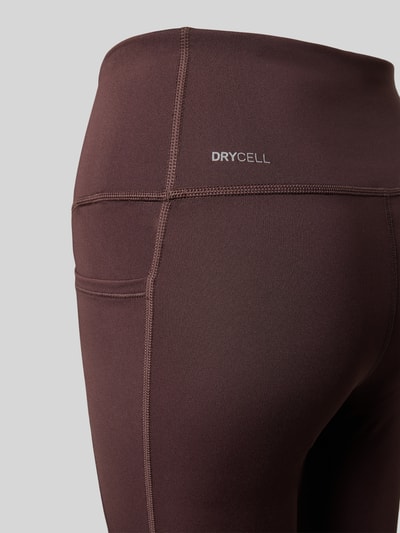 Frauenmodel trägt Flared Leggings mit Logo von PUMA in Dunkelbraun, dehnbarer Material-Mix, High Waist, seitliche Nahtdetails, Nahaufnahme Hüfte.