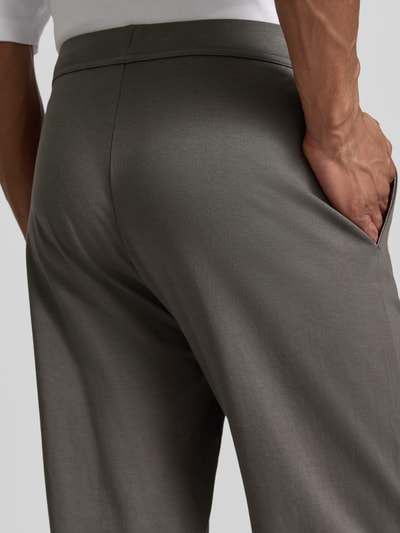 Mężczyzna nosi Lounge-Hose mit elastischem Bund und Eingrifftaschen von Christian Berg Men, bawełna, krój regular fit, wpuszczane kieszenie, długość wewnętrzna nogawki w rozmiarze M 40 cm, zbliżenie na tylne kieszenie.