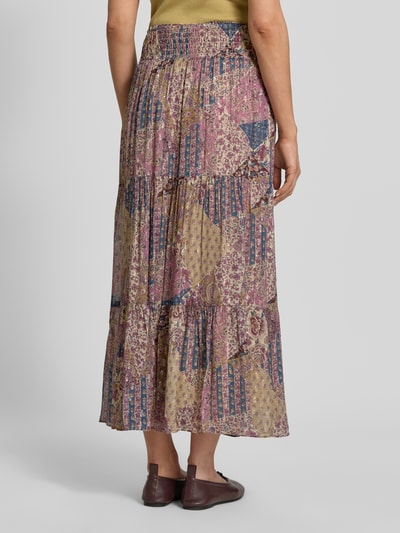 Frauenmodel trägt Maxirock aus Viskose mit Kordelzug Modell 'PITSY' von Bash, A-Linie, Volantsaum, florale Muster, Ganzkörperansicht Rückansicht.