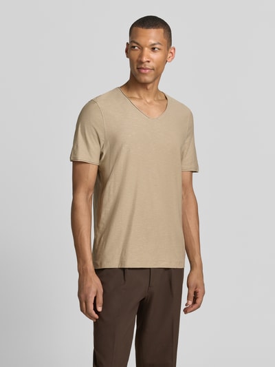 Męski model nosi Regular Fit T-Shirt mit V-Ausschnitt von MCNEAL, bawełna, krój regular fit, dekolt w serek, zrolowany brzeg, długość tyłu 70 cm w rozmiarze M, beżowy, gładka tekstura, Ganzkörperansicht von vorne.