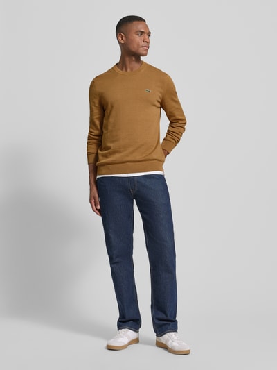 Männermodel trägt Regular Fit Strickpullover aus Baumwoll-Mix von Lacoste in Unifarben mit Label-Patch, Rundhals, Langarm, Gerippt, Ganzkörperansicht von vorne.