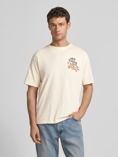 Männermodel trägt T-Shirt mit Label-Stitching von Scotch & Soda in Creme, Reine Baumwolle, Regular-Fit, Gerippter Rundhalsausschnitt, Ganzkörperansicht von vorne.