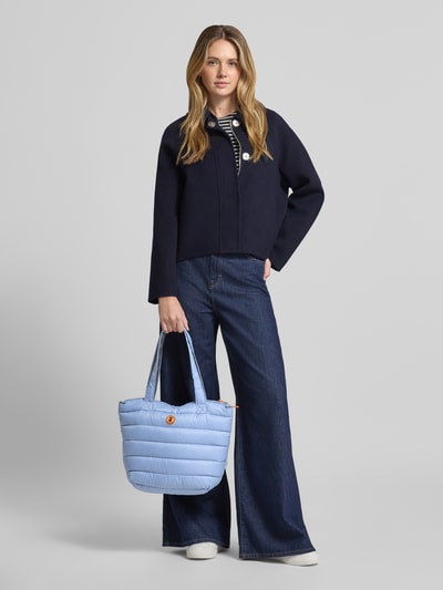 Frauenmodel trägt Shopper mit Label-Detail Modell 'CARON' von SAVE THE DUCK, hellblau gesteppte Oberfläche, Ganzkörperansicht von vorne.