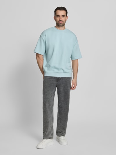 Männermodel trägt Oversized T-Shirt mit Rundhalsausschnitt von Lindbergh in Hellblau aus Baumwoll-Mix, Label-Detail, Rückenlänge 70 cm, Ganzkörperansicht von vorne.