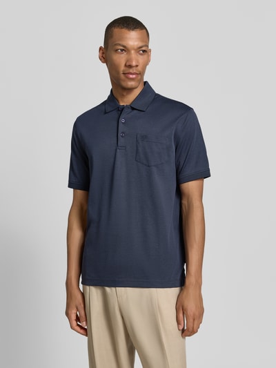 Männermodel trägt Regular Fit Poloshirt mit Brusttasche und Label-Stitching von bugatti in Dunkelblau, Knopfleiste, Polokragen, Rückenlänge bei Größe M 70 cm, Ganzkörperansicht von vorne.