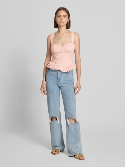 Frauenmodel trägt Slim Fit Top mit Allover-Spitzenbesatz von Gina Tricot in Hellrosa mit Zierschleife, Spaghettiträger, Ganzkörperansicht von vorne.
