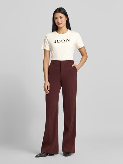 Frauenmodel trägt T-Shirt mit Label-Print Modell 'Tanna' von JOOP! aus reiner Baumwolle im Regular-Fit mit Rundhalsausschnitt, Ganzkörperansicht von vorne.