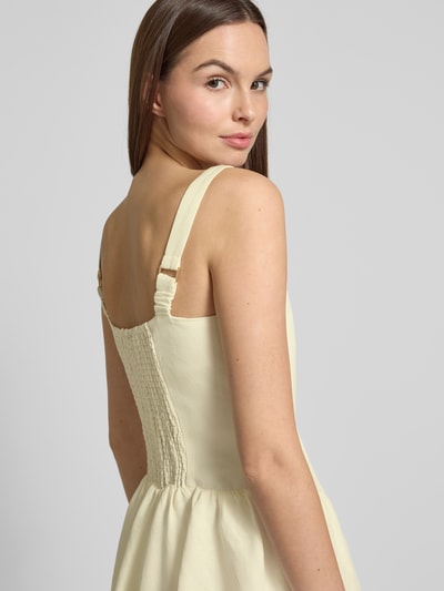 Frauenmodel trägt Cocktailkleid aus Leinen-Mix mit Smok-Details Modell 'Heidi' von Forever New, hellgelb, ausgestellter Schnitt, Minikleid, Rundhalsausschnitt, rückseitige Smok-Details, Leinen-Viskose-Mix, Nahaufnahme Rückenansicht.