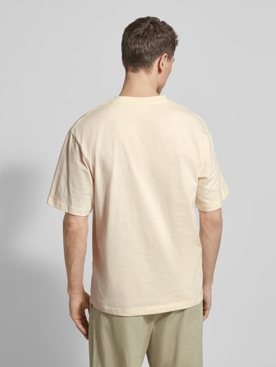 Męski model ma na sobie Relaxed Fit T-Shirt mit Logo-Print Modell 'Liam' od Wood Wood z czystej bawełny, kremowy kolor, widok całej sylwetki z tyłu