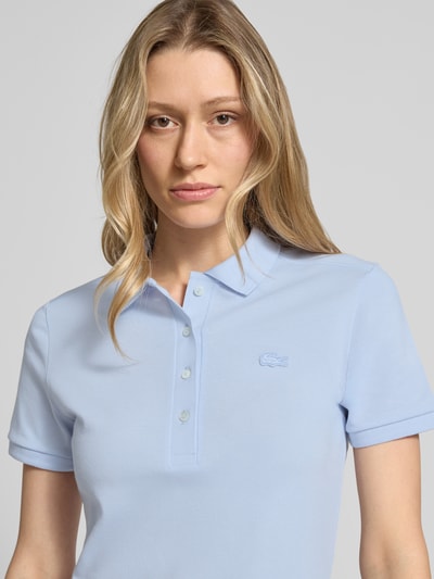 Frauenmodel trägt Slim Fit Polokleid aus Baumwoll-Mix von Lacoste in Hellblau, unifarben, Piqué-Textur, Nahaufnahme Oberkörper.