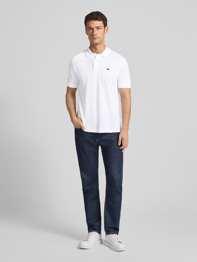 Männermodel trägt Poloshirt mit Label-Stitching Modell 'L.12.12 CORE' von LACOSTE aus reiner Baumwolle, Unifarbenes-Design, Ganzkörperansicht von vorne.
