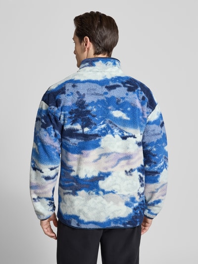 Männermodel trägt Regular Fit Pullover mit Logo-Patch von Columbia in blauer Fließ-Optik, elastische Abschlüsse, Ganzkörperansicht Rückansicht.