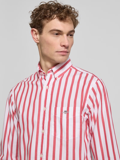 Männermodel trägt Slim Fit Freizeithemd mit Brusttasche von Gant, rot-weiß gestreift, reine Baumwolle, Nahaufnahme Oberkörper.