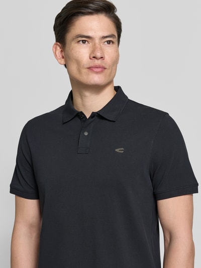 Mannelijk model draagt Regular Fit Poloshirt in unifarbenem Design van camel active, katoen-elastaanmix, knoopsluiting, logo, effen zwart, bovenlichaam close-up van voren