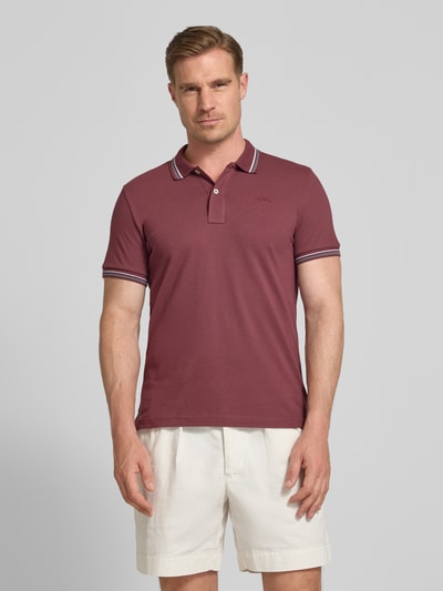 Męski model nosi Slim Fit Poloshirt mit Kontraststreifen von Geox z mieszanki bawełny, kołnierzyk polo, listwa guzikowa, krój slim fit, paski w kontrastowym kolorze, długość tyłu w rozmiarze M: 69 cm, Ganzkörperansicht von vorne.