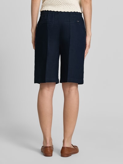 Frauenmodel trägt Leinenshorts mit Eingrifftaschen von Christian Berg Woman in Dunkelblau, Reines Leinen, Regular-Fit, Bügelfalten, Bundweite 40 cm, Innenbeinlänge 22 cm, Ganzkörperansicht Rückansicht.