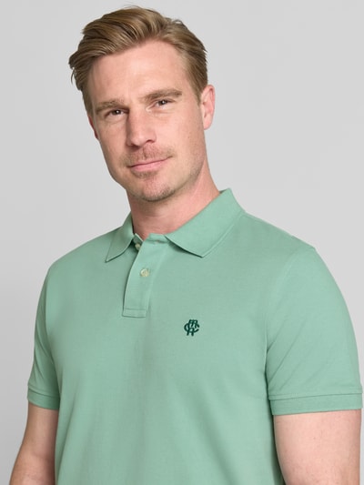 Männermodel trägt Regular Fit Poloshirt mit Label-Stitching von MCNEAL aus Reine Baumwolle, Knopfleiste, Nahaufnahme Oberkörper. Rückenlänge 70 cm bei Größe M.