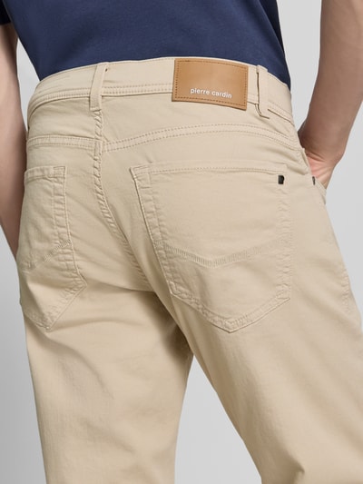Männermodel trägt Jeans mit Label-Detail Modell 'Lyon' von Pierre Cardin aus Baumwoll-Mix mit Stretch-Anteil, Nahaufnahme Rückansicht. Herren Jeans in Beige mit Eingrifftaschen, Regular-Fit, Bundweite bei Größe 32/32: 41 cm, Innenbeinlänge: 80 cm.