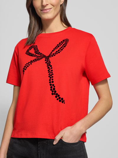 Frauenmodel trägt Oversized T-Shirt aus reiner Baumwolle von Tom Tailor Denim, Optik: Unifarben, Passform: Oversized, Motiv-Print, Rundhals, Kurzarm, Material: Baumwolle, leuchtend rot mit schwarzem Motiv, glatte Textur, Nahaufnahme Oberkörper.